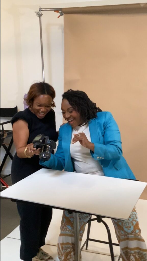 Behind the scenes of Atlanta brand photography session showing photographer Carlisa Georgeanne in turquoise blazer reviewing photos with client, demonstrating collaborative three-phase photography process
